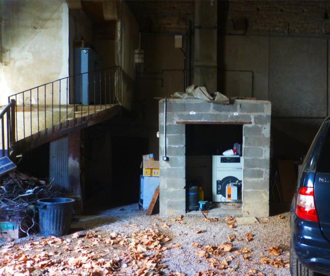 Avant travaux, chaufferie en bloc de béton creux ouverte dans un ancien pressoir